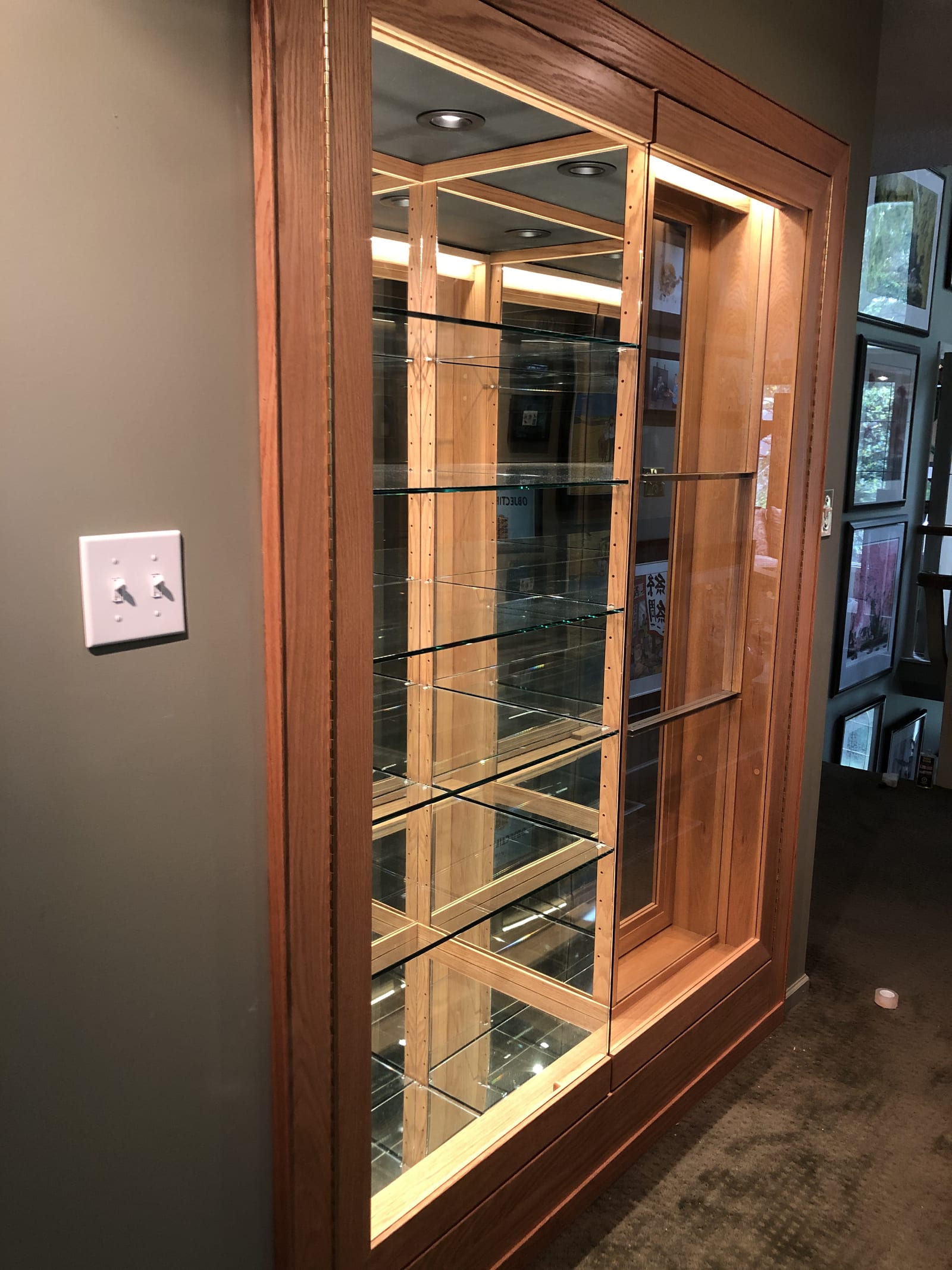 Custom oak display cabinet with mirrored back, glass shelving, and integrated lighting