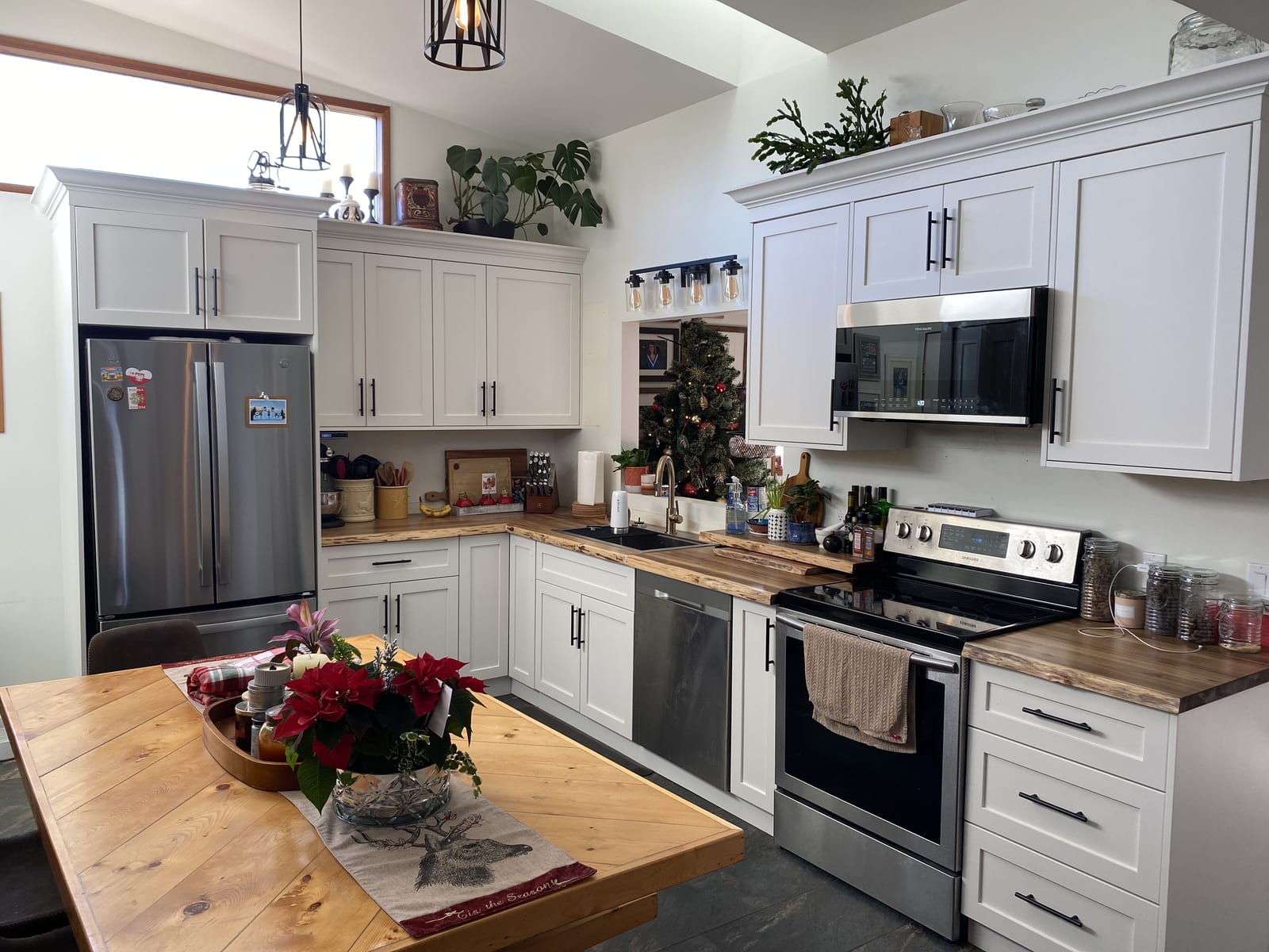 White shaker kitchen with live-edge wood countertops, black hardware, and a farmhouse island table