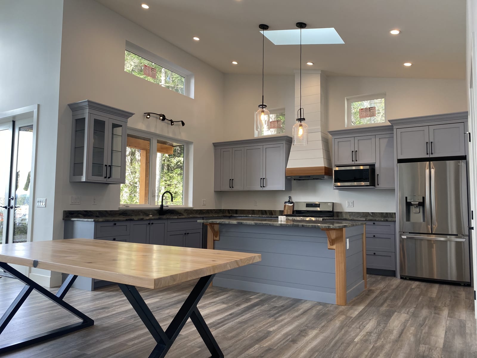 Vaulted-ceiling kitchen with grey shaker cabinets, a skylight, and a matching island