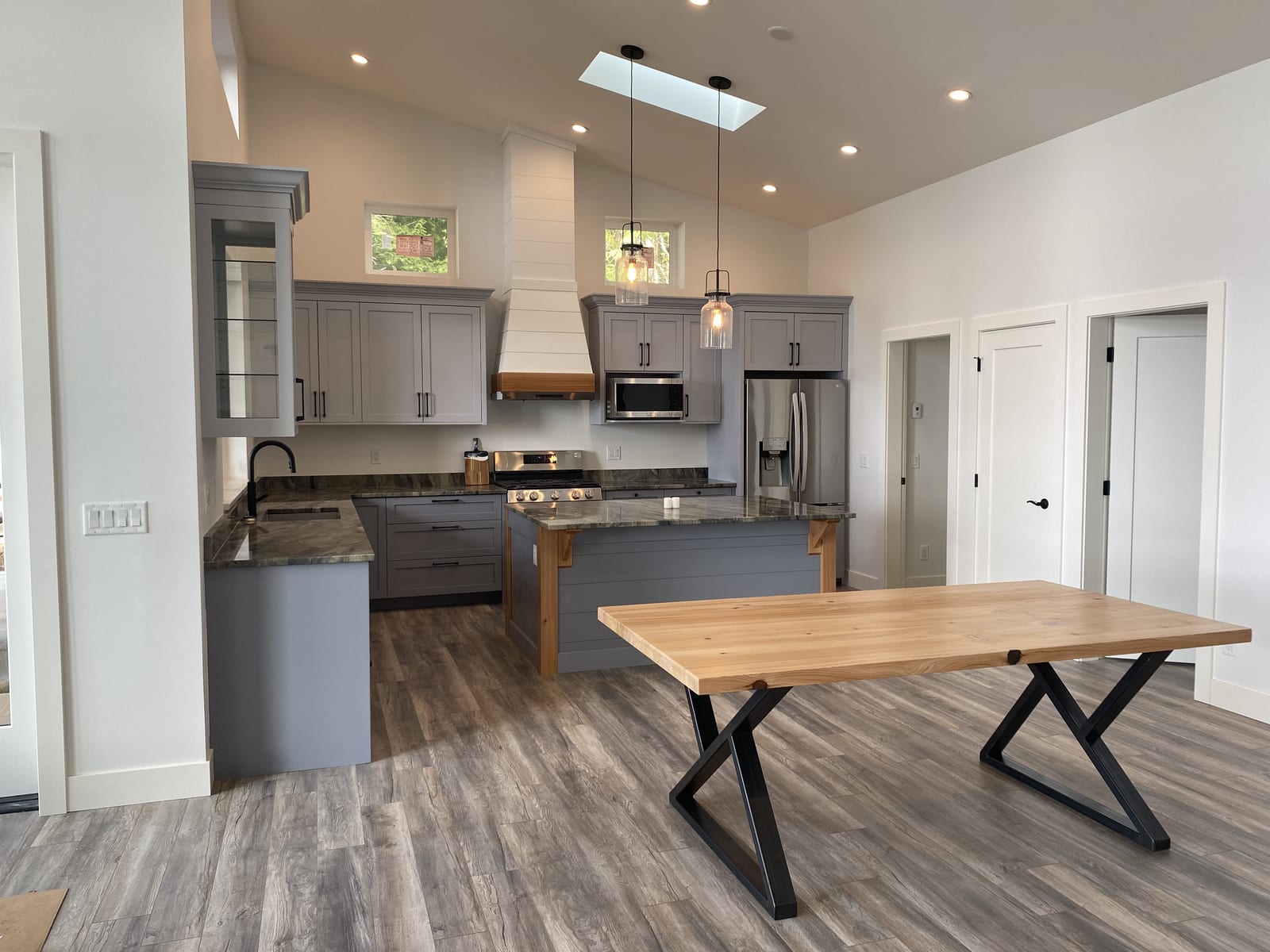 Grey shaker kitchen with a waterfall island and a matching solid-wood dining table on steel legs