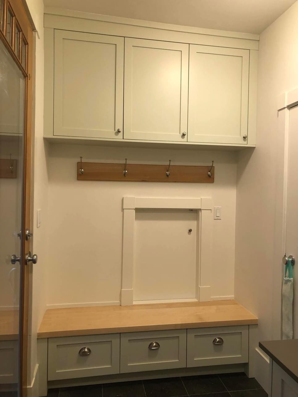 Mudroom built-in with painted cabinets, a wood bench top, drawers, and a coat hook rail
